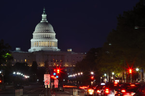 Capitol building at night with street and lawmakers